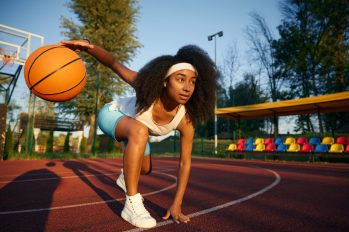 Young female basketball player in low start position dribbling ball